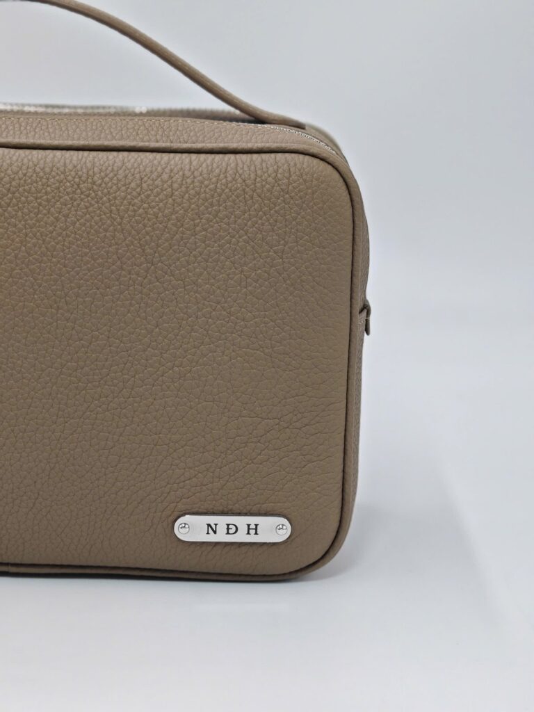 Tấm kim loại khắc tên viết tắt trên túi golf cầm tay TP Valet Clutch, quà tặng thầy giáo chơi golf